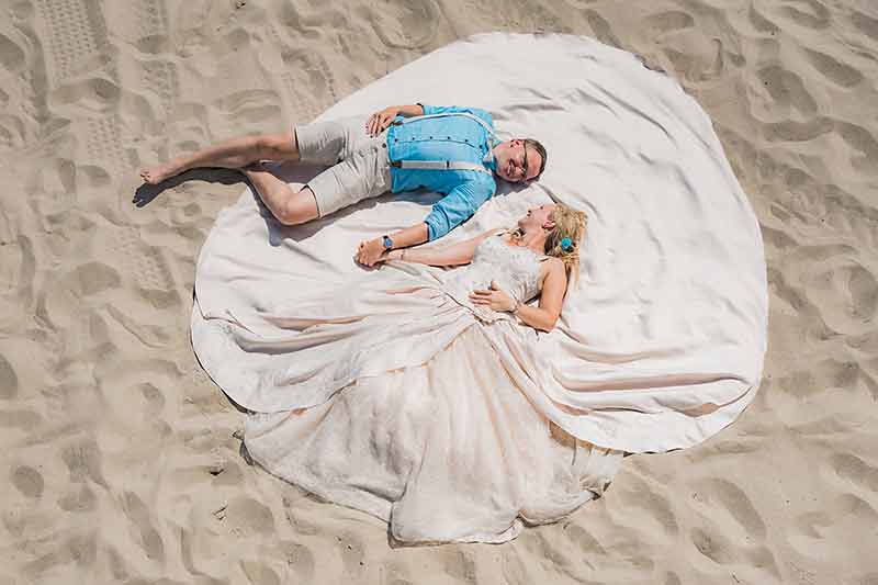 Brautpaar liegt im Sand
